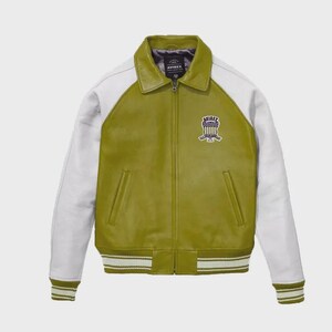 May include: Olive green leather jacket with white sleeves and collar. Features a zip-up front, side pockets, and a striped hem and cuffs. The jacket has a patch on the chest with the text "AVIREX".