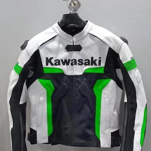 May include: A white, black, and green Kawasaki motorcycle jacket. The jacket features the Kawasaki logo in green across the chest. Black panels are on the sides and sleeves, with green accents. The jacket is hanging on a hanger.