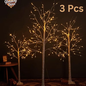 May include: Three artificial birch trees with warm white LED lights. The trees have white trunks and branches, and are illuminated with small, bright lights. The text "3 Pcs" is visible in the image. The logo for "Glowing Topia" is in the upper left corner.