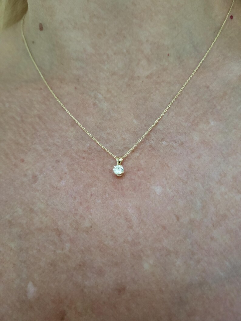 May include: A simple gold chain necklace with a small, round, clear gemstone pendant.
