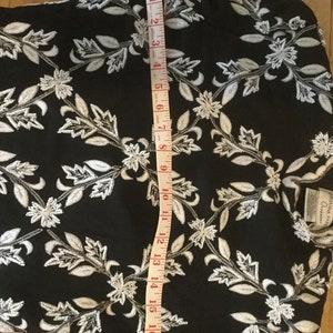 Puede incluir: Vestido negro con bordado floral blanco y una cinta m&eacute;trica que muestra una longitud de 45,7 cm.