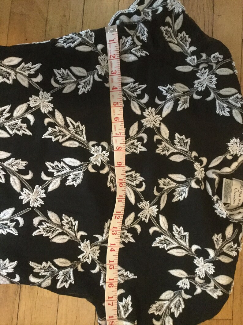 Puede incluir: Vestido negro con bordado floral blanco y una cinta m&eacute;trica que muestra una longitud de 45,7 cm.