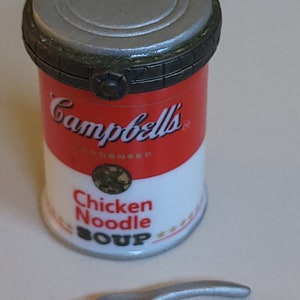 May include: A miniature ceramic replica of a Campbell's Chicken Noodle Soup can with a silver lid and a small silver spoon.