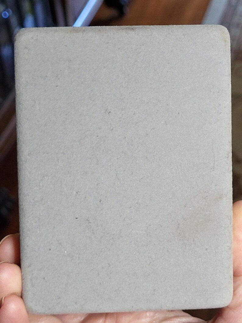 May include: A gray, rectangular, textured coaster.