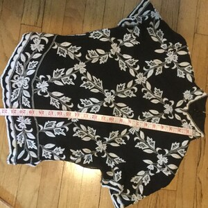 Puede incluir: Top negro y blanco bordado con un patr&oacute;n floral. El top tiene mangas cortas y un dobladillo festoneado.