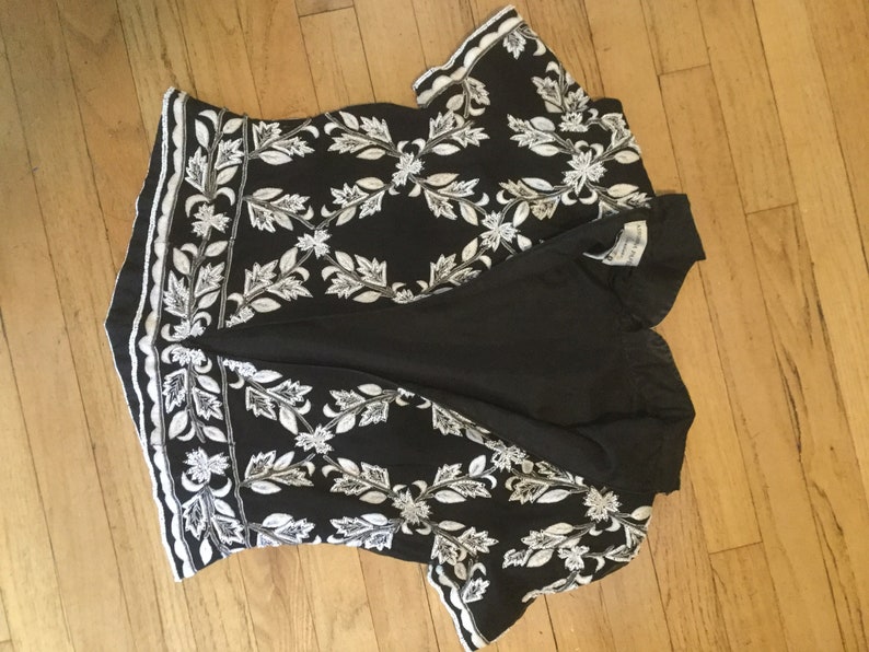 Puede incluir: Top de manga corta negro y blanco bordado con un patr&oacute;n floral.