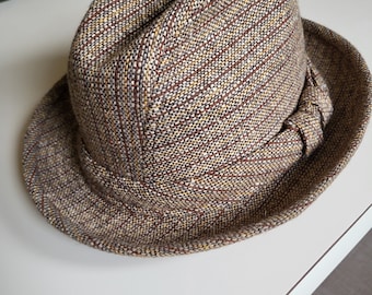 May include: A brown and tan tweed fedora hat with a brown ribbon.