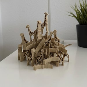 Könnte beinhalten: Eine Ansammlung von hellbraunen, 3D-gedruckten Giraffenfiguren, die in einem Haufen gestapelt sind. Jede Giraffe weist eine geometrische Gitterstruktur mit sichtbaren Hals-, Körper- und Beinsegmenten auf. Die Figuren bilden einen dichten Haufen.