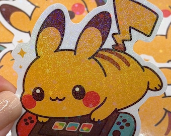 Könnte beinhalten: Ein gelber Pikachu-Aufkleber mit holografischem Finish. Der Aufkleber zeigt Pikachu beim Spielen eines Videospiels auf einem Controller im Nintendo Switch-Stil. Der Aufkleber hat einen weißen Rand und ist von anderen ähnlichen Aufklebern umgeben.