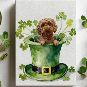 May include: Watercolor painting of a brown dog inside a green leprechaun hat, surrounded by shamrocks. The hat has a black band with a gold buckle. The artwork is on a canvas, with white flowers and green leaves in the background.