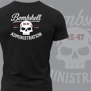 May include: Black t-shirt with a white skull graphic and the words "Bombshell Administration." The skull has the numbers "45-47" in red. The shirt is a crew neck style.
