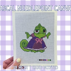 May include: Hand-painted needlepoint canvas depicting Pascal the chameleon from Tangled. The canvas has an 18-mesh count and shows Pascal in a purple dress with a pink bow. The text "Pascal Needlepoint Canvas" is at the top of the canvas.