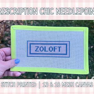 May include: A needlepoint canvas with the text "ZOLOFT" inside a blue rectangle, set against a white mesh background. The canvas has a bright green border. The text "PRESCRIPTION CHIC NEEDLEPOINT" and "STITCH PRINTED | 13 & 18 MESH CANVAS" are also visible.