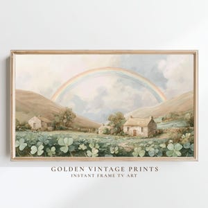 May include: A framed vintage landscape painting featuring a rainbow arching over a valley with cottages and fields of clover. The artwork has a soft color palette of greens, browns, and blues. The text "GOLDEN VINTAGE PRINTS" and "INSTANT FRAME TV ART" is at the bottom.