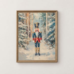 May include: An oil painting in a gold frame depicting a nutcracker figure standing in a snowy forest. The nutcracker wears a dark blue uniform with red accents, gold trim, and a tall hat. The background shows snow-covered trees in winter.