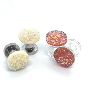 May include: Three pairs of iridescent crystal earrings with silver posts. The earrings are in white, pink, and orange.