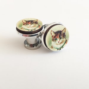 May include: Two silver knob pulls with a round wooden base featuring a vintage image of a cat with brown and white fur.