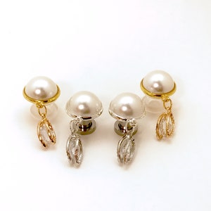 May include: Three pairs of pearl earrings with dangling crystal charms. The earrings are available in gold, silver, and rose gold.
