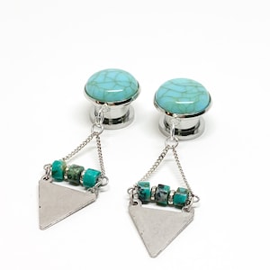 May include: A pair of turquoise and silver ear gauges with a dangling triangle charm and turquoise beads.