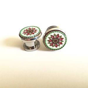 May include: Two decorative cabinet knobs with a floral design. The knobs have a silver base and a round top with a white background, a red and gold floral pattern, and a green border.