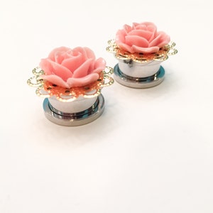 K&ouml;nnte beinhalten: Ein Paar silberne Ohrdehner mit rosa Rosenakzenten und goldenen Filigranen. Die Rosen haben eine glitzernde Oberfl&auml;che.