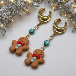 May include: A pair of gold ear cuffs with gingerbread man charms and turquoise beads. The gingerbread men have red bows and white buttons.