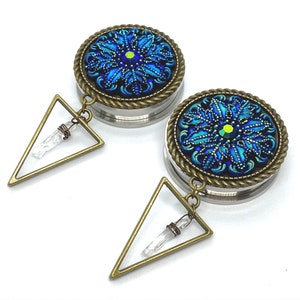 May include: A pair of blue and gold ear gauges with a crystal dangle. The gauges feature a blue and green mandala design with a gold trim.