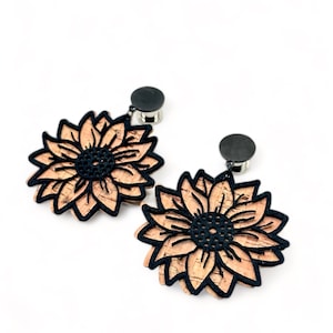 May include: A pair of cork and black sunflower earrings with a black metal backing.