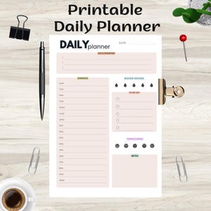 May include: A printable daily planner with the text "Printable Daily Planner" at the top. The planner includes sections for top priorities, a schedule, water intake, a to-do list, and notes. A pen, paper clips, and a cup of coffee are also visible.