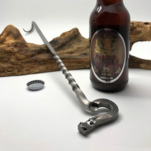 May include: A silver bottle opener with a dragon head design. The opener is twisted and has a hook on the end. A bottle of Unibroue beer is in the background.