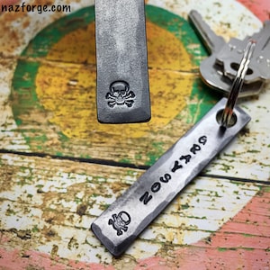 May include: Two silver metal keychains with a skull and crossbones design. One keychain has the word "NOSY" engraved on it.