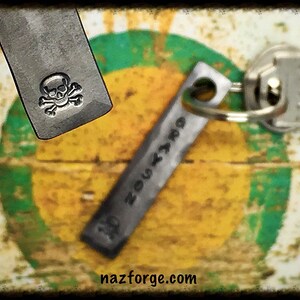 May include: Two metal keychains, one with a skull and crossbones design and the other with the text "nazforge.com".
