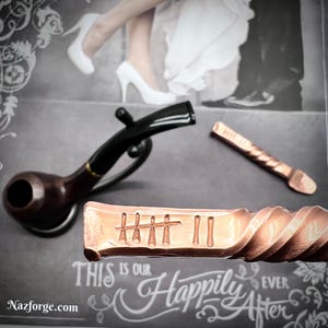 May include: A copper pipe with a twisted design and engraved with the words "This is our happily ever after".