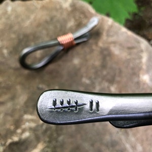 May include: A silver metal key chain with a decorative design on the end. The design features a series of small, raised dots and lines.