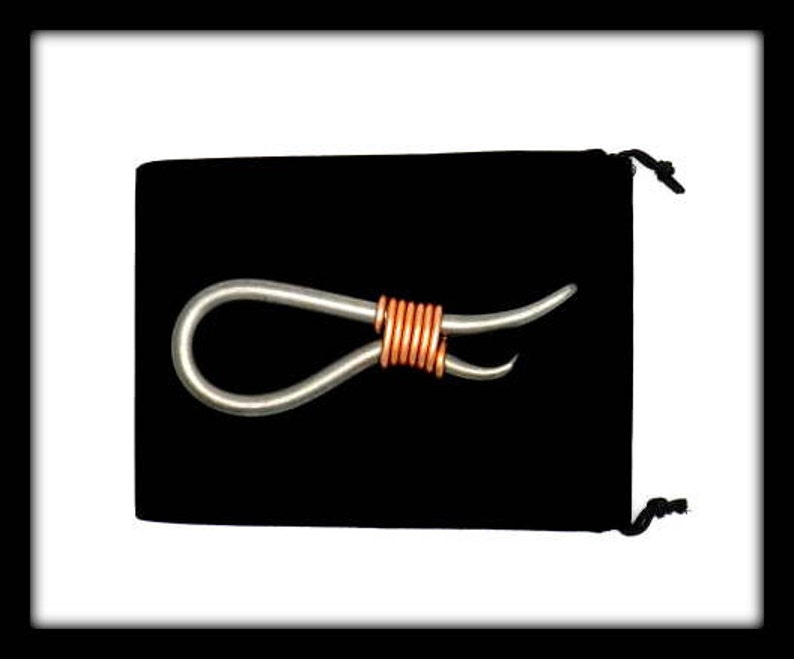 May include: A silver metal loop with a copper wire wrapped around the center. The loop is on a black velvet background.