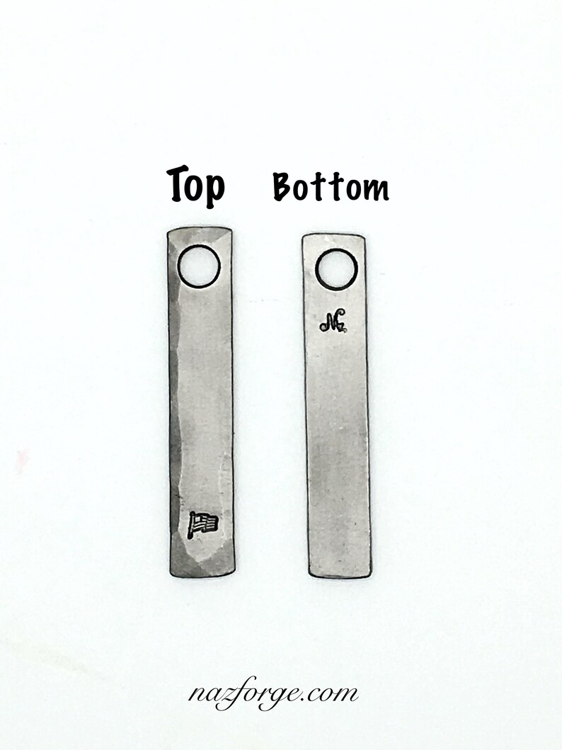 May include: Two rectangular metal pendants with a hammered texture. One pendant has a small flag design, the other has an initial. Both have a hole at the top. The words "Top" and "Bottom" are above the pendants. The website nazforge.com is at the bottom.