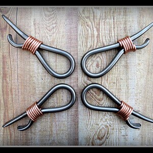 May include: Four metal bottle openers with copper wire wrapped around the handles. The openers are arranged in a cross pattern on a wooden surface.