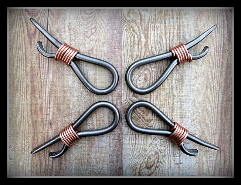 May include: Four metal bottle openers with copper wire wrapped around the handles. The openers are arranged in a cross pattern on a wooden surface.