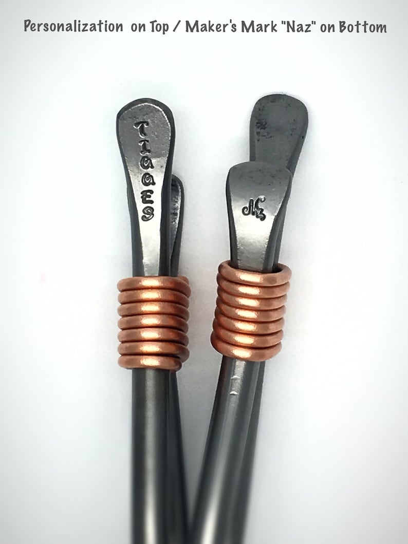 May include: Two silver metal hair clips with copper wire wrapped around the middle. The top of the clips are engraved with the words "TIGGES" and "Naz".