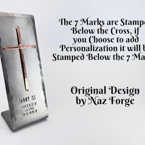 May include: A hammered silver-toned metal stand featuring a copper-colored cross, seven vertical stamped marks, and the text "SHIRLEY AND TERRY". Text on the right reads: "The 7 Marks are Stamped Below the Cross, if you Choose to add Personalization it will be Stamped Below the 7 Marks. Original Design by Naz Forge."