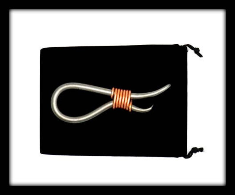 May include: A silver metal loop with a copper wire wrapped around the center. The loop is on a black velvet background.