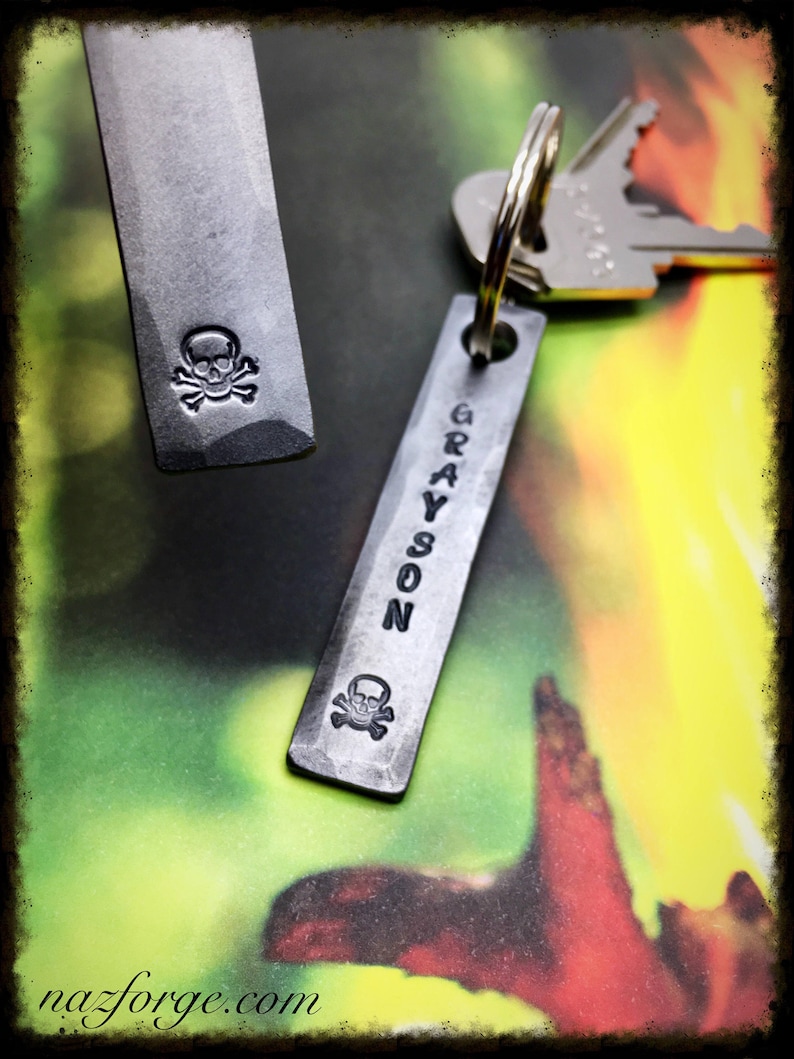 May include: Two metal keychains with a skull and crossbones design. One keychain has the name "GRAYSON" engraved on it.