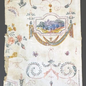 May include: Antique wallpaper fragment with a repeating pattern of floral bouquets, landscape vignettes, and decorative flourishes in shades of yellow, blue, pink, and green. The aged paper has visible wear and tear.