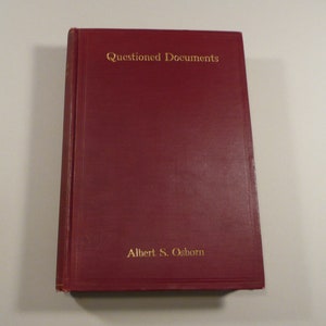 May include: A burgundy hardcover book with gold lettering on the spine and front cover. The title is "Questioned Documents" and the author is "Albert S. Osborn".