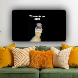 May include: A black wall art piece with the text "Welcome to my crib" above a duckling. The art hangs above a green sofa with yellow and patterned pillows. A gold and mint green floor lamp is to the left.