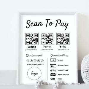 Könnte beinhalten: Ein gerahmtes Schwarz-Weiß-Schild mit dem Text "Scan To Pay" und QR-Codes für Venmo, PayPal und Pay. Es listet auch akzeptierte Zahlungsmethoden auf: Bargeld, Kreditkarte, Google Pay, Mastercard und Visa. Das Schild enthält Social-Media-Symbole.