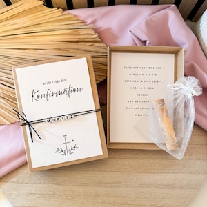 May include: A Confirmation gift set featuring a greeting card with the word "Konfirmation" and the name "MORITZ". The set includes a small gift in a sheer bag and a card with text inside a box.