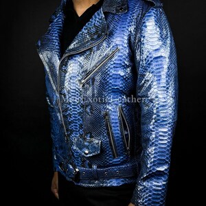 Puede incluir: Chaqueta de cuero azul con textura de piel de serpiente, de estilo motero cl&aacute;sico. Cuenta con cuello con solapas, cierre de cremallera asim&eacute;trico, m&uacute;ltiples bolsillos con cremallera y cintur&oacute;n en la cintura. La chaqueta es de un azul vibrante con detalles m&aacute;s oscuros.
