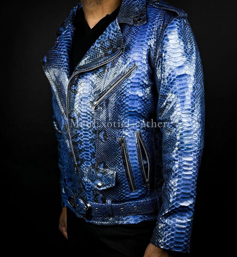 Puede incluir: Chaqueta de cuero azul con textura de piel de serpiente, de estilo motero cl&aacute;sico. Cuenta con cuello con solapas, cierre de cremallera asim&eacute;trico, m&uacute;ltiples bolsillos con cremallera y cintur&oacute;n en la cintura. La chaqueta es de un azul vibrante con detalles m&aacute;s oscuros.