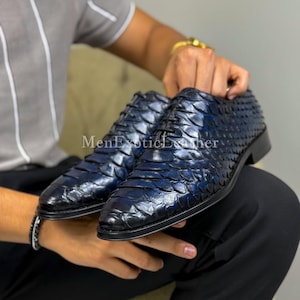 Könnte beinhalten: Ein Paar marineblaue Lederschuhe mit einem strukturierten, schuppenartigen Muster. Die Schuhe haben ein klassisches Schnürdesign und einen niedrigen Absatz. Der Text "MenExoticLeather" ist sichtbar.